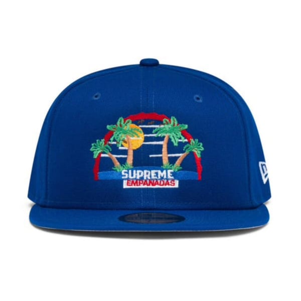 Blue Supreme Empanadas baseball cap with an embroidered tropical sunset and palm trees logo.